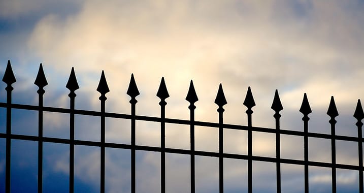 hero-about a-black-iron-fence-with-a-cloudy-sky-in-the-background-nhtdgytgzky
